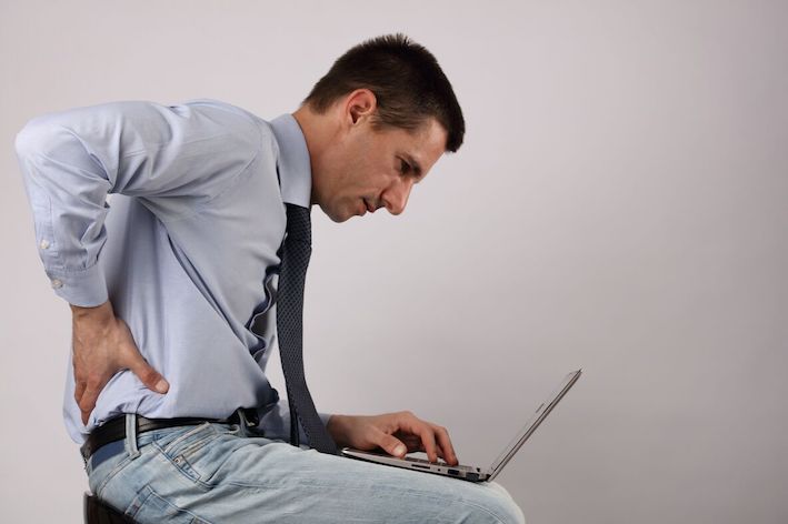 man with sore back holding laptop